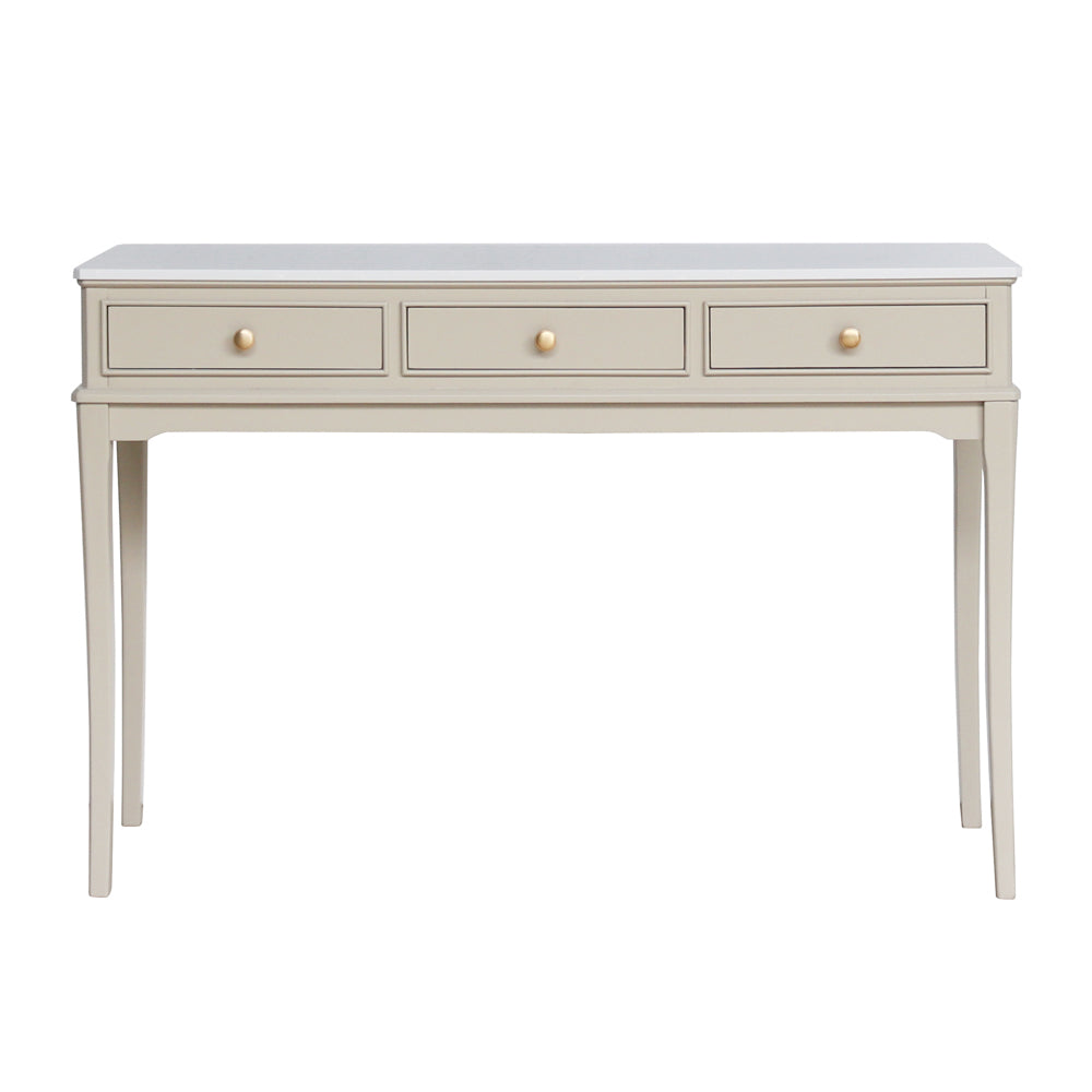 A console table with three drawers, featuring a light gray top and a warm beige body with gold-toned round knobs and slender legs.