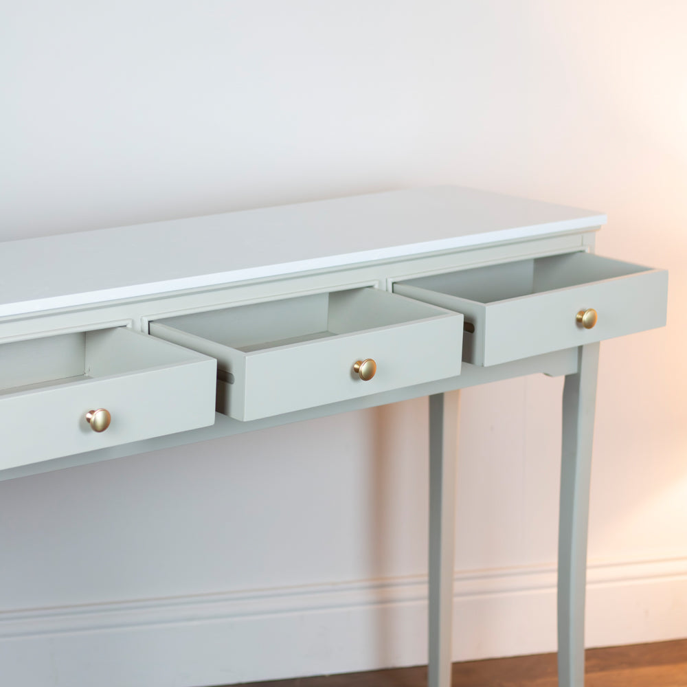 Monroe 3 Drawer Console Table in Stone console table with three drawers and brass knobs on a white wall background
