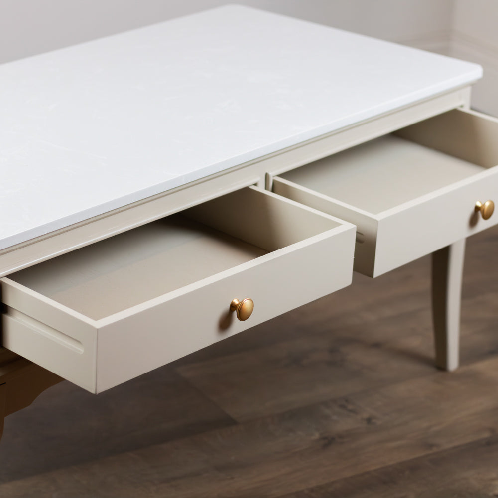 Monroe Coffee Table in Stone with two open drawers and small round gold knobs, set against a dark wood floor.