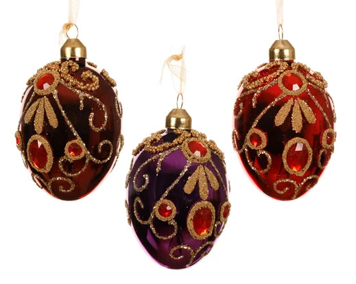 Three luxury egg-shaped glass Christmas baubles with enamel finish, decorated with gold glitter, red beads, and diamond accents – assorted red, oxblood, and fig tones.