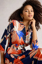 Woman wearing a colorful floral patterned shirt against a neutral background