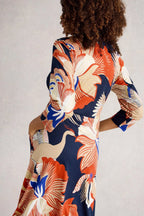 Person wearing a colorful floral dress with a neutral background