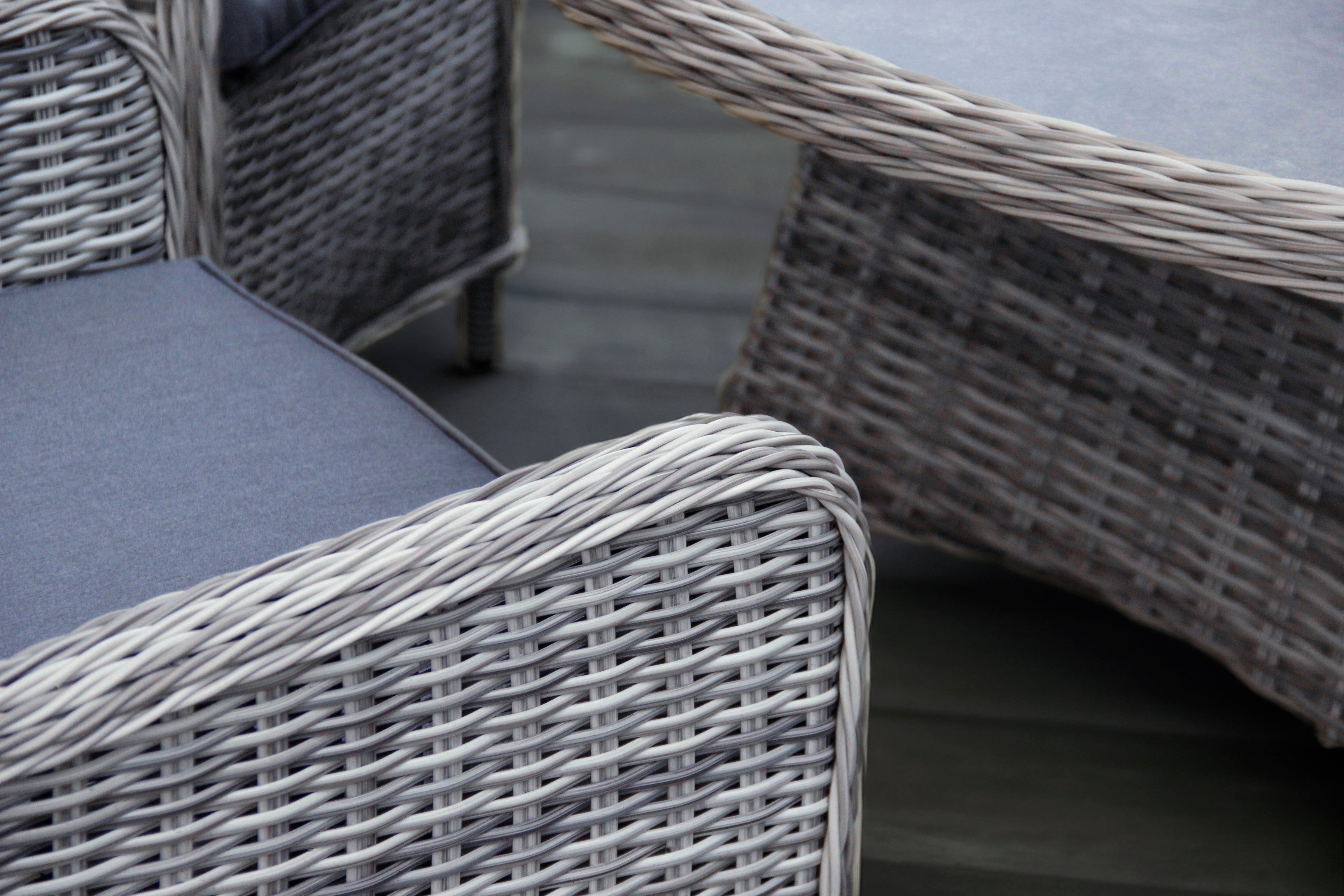 Gray wicker outdoor furniture set with cushions on a wooden deck.