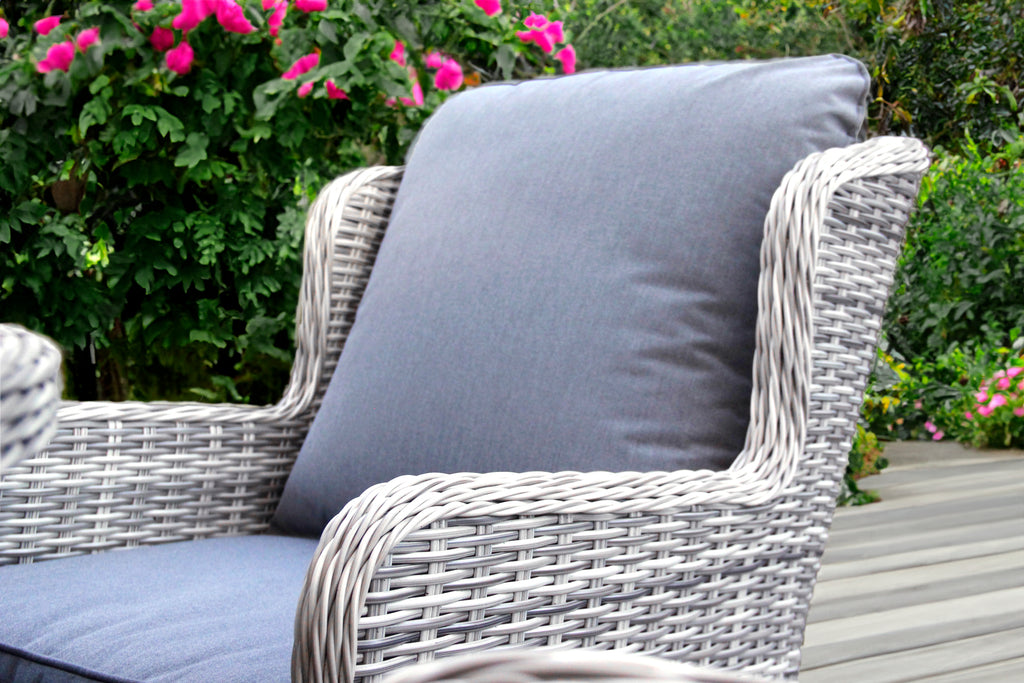 Wicker chair with gray cushion in a garden setting