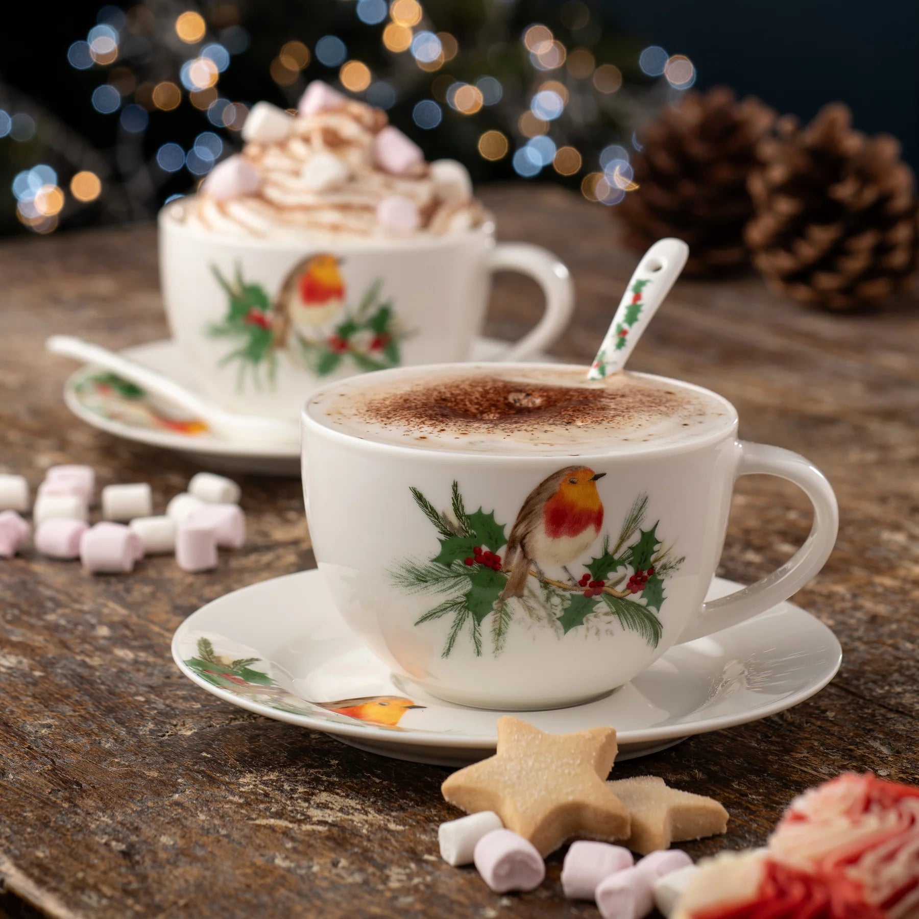 Christmas-themed cup of hot chocolate with whipped cream and a cookie on a wooden table.