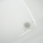 A close-up of a translucent white plastic cap or connector piece resting on a glossy white surface.