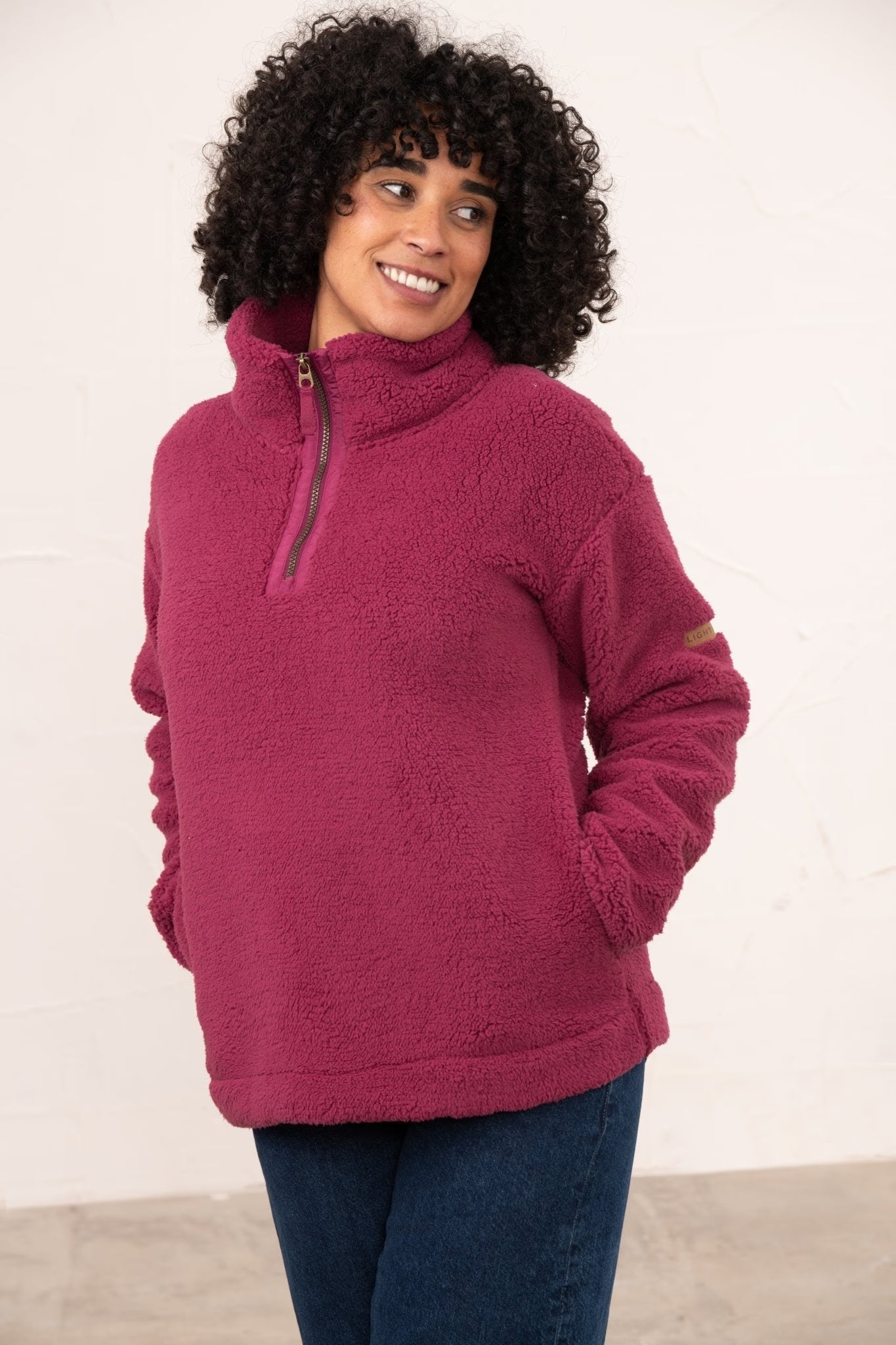 Woman wearing a pink fleece pullover against a white background