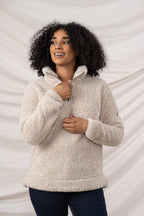 Woman wearing a beige sherpa pullover against a neutral background