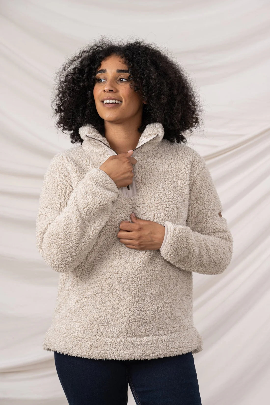 Woman wearing a beige sherpa pullover against a neutral background