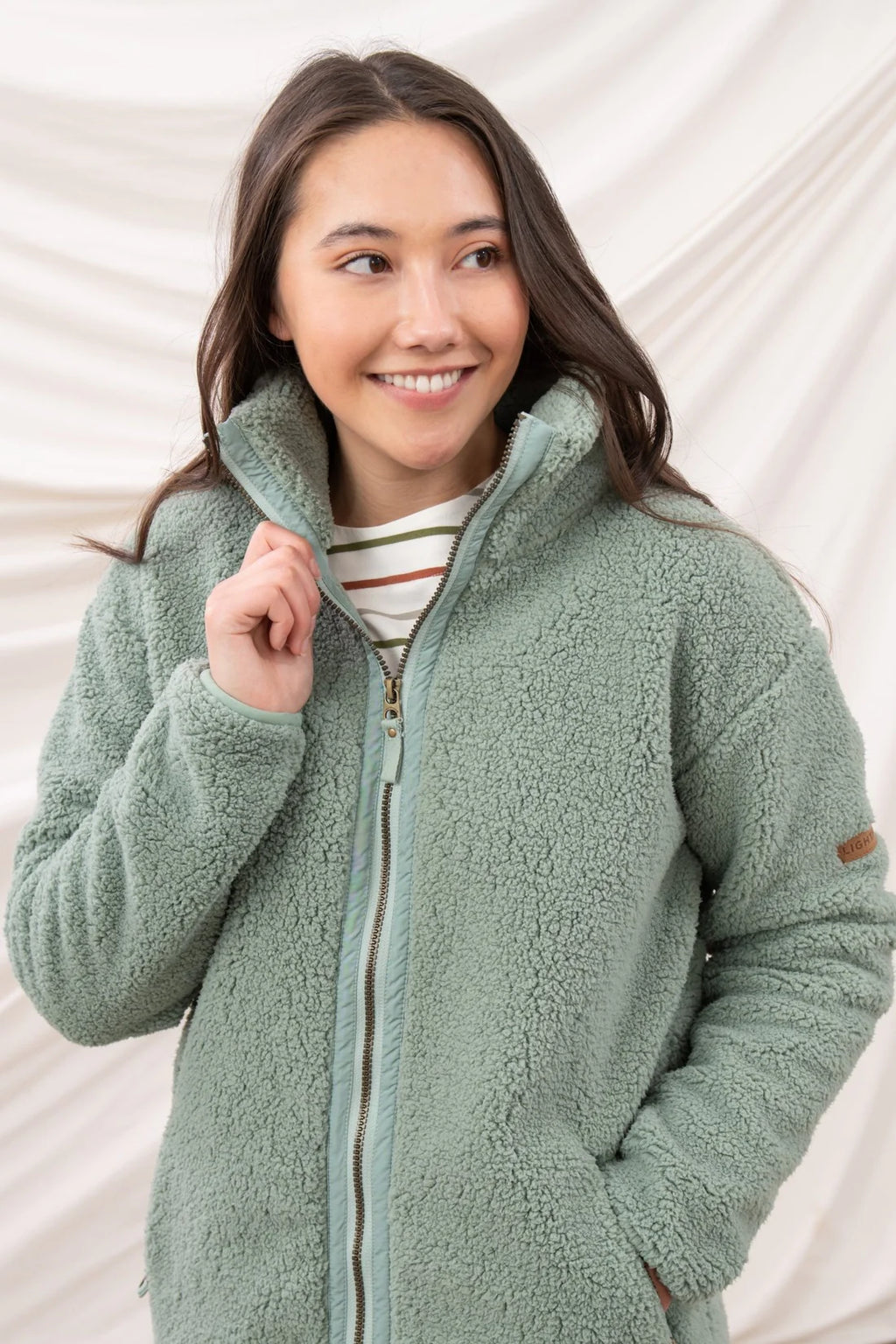 Woman wearing a green fleece jacket against a white background