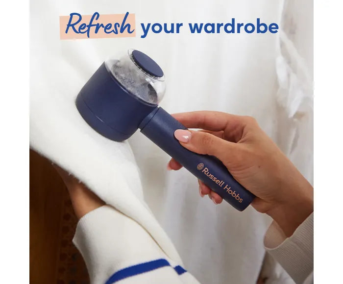 Hand holding a blue fabric shaver with 'Russell Hobbs' branding, text 'Refresh your wardrobe' above.