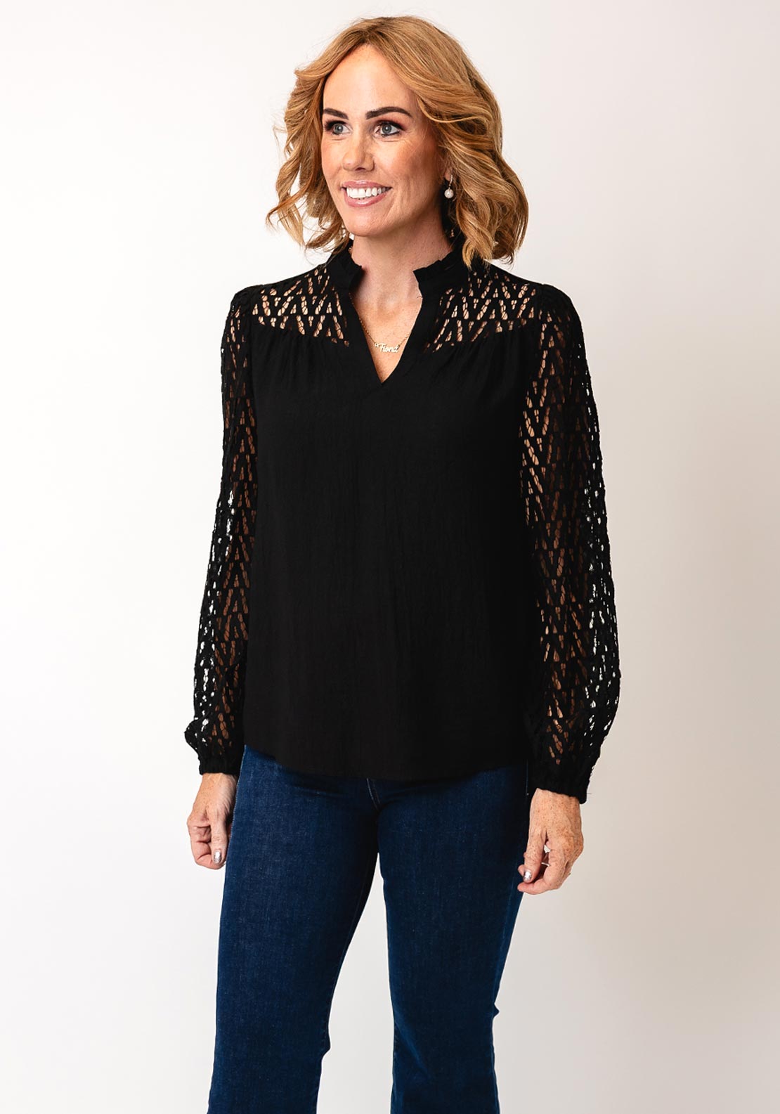 Fransa Bess blouse in black with laser‑cut chevron sleeves and frill‑trimmed V‑neck, loose hip‑length fit