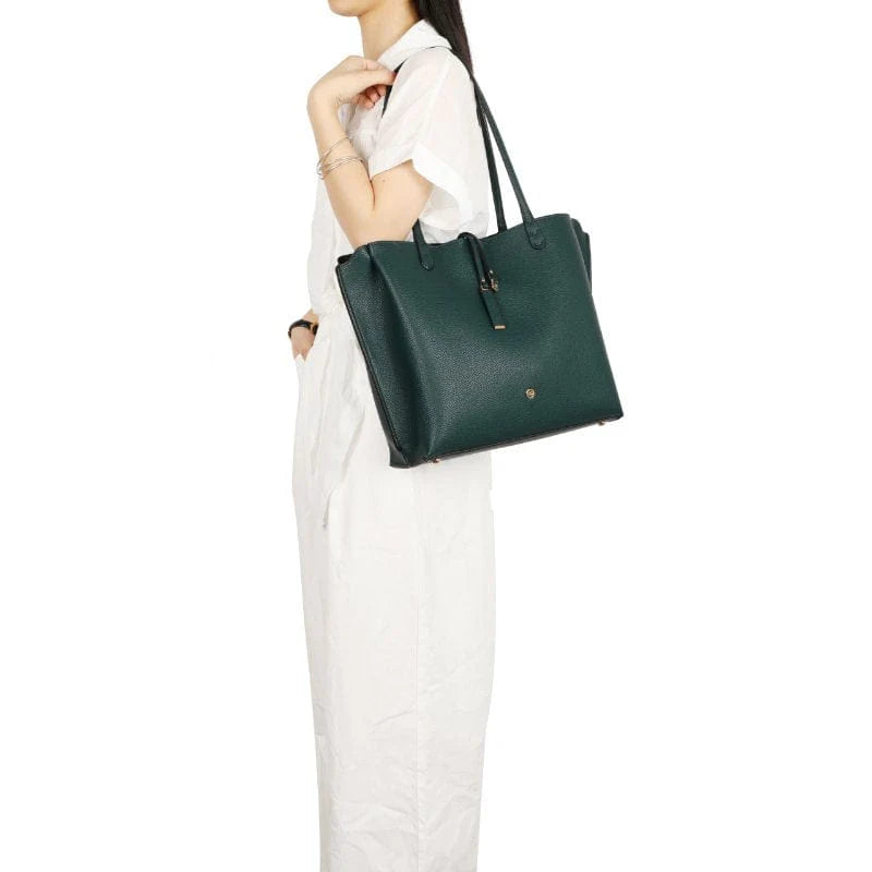 Person holding a green tote handbag against a white background