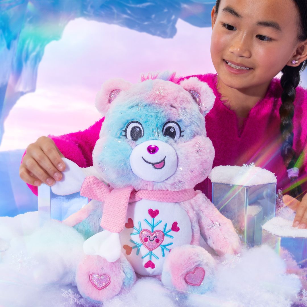 Child holding a colorful teddy bear with a heart design in a snowy scene