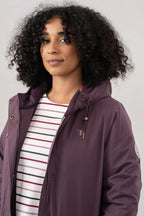 Woman wearing a purple jacket over a striped shirt against a plain background