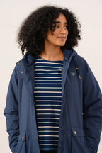 Woman wearing a navy blue hooded jacket over a striped shirt on a white background