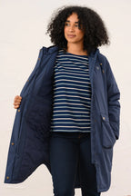 Woman wearing a navy blue coat over a striped shirt on a white background