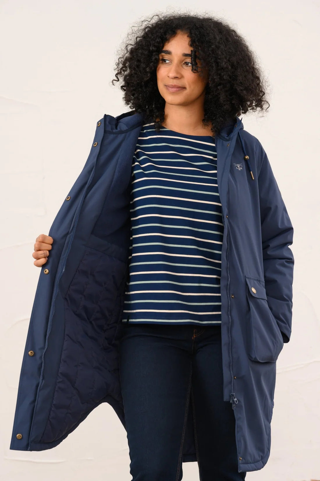 Woman wearing a navy blue coat over a striped shirt on a white background
