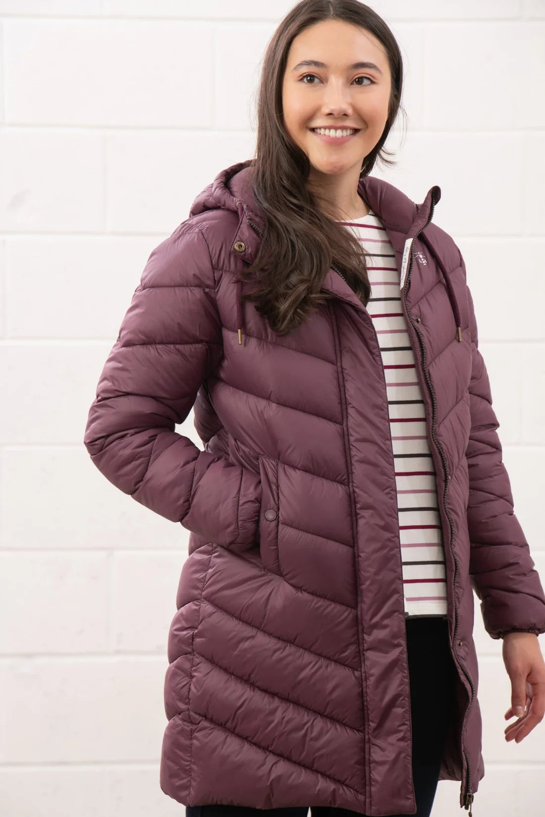 Woman wearing a purple puffer coat against a white background