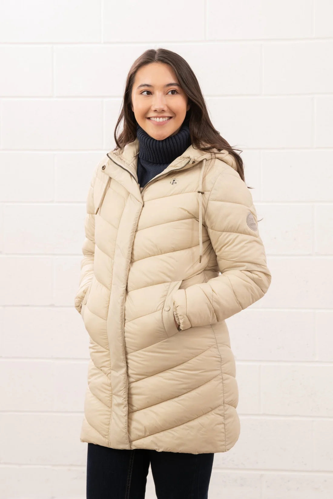 Woman wearing a beige puffer jacket against a white background