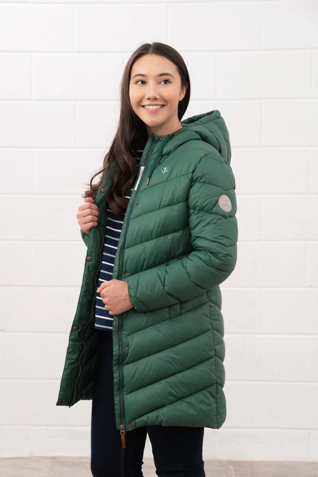 Woman wearing a green puffer coat against a white background