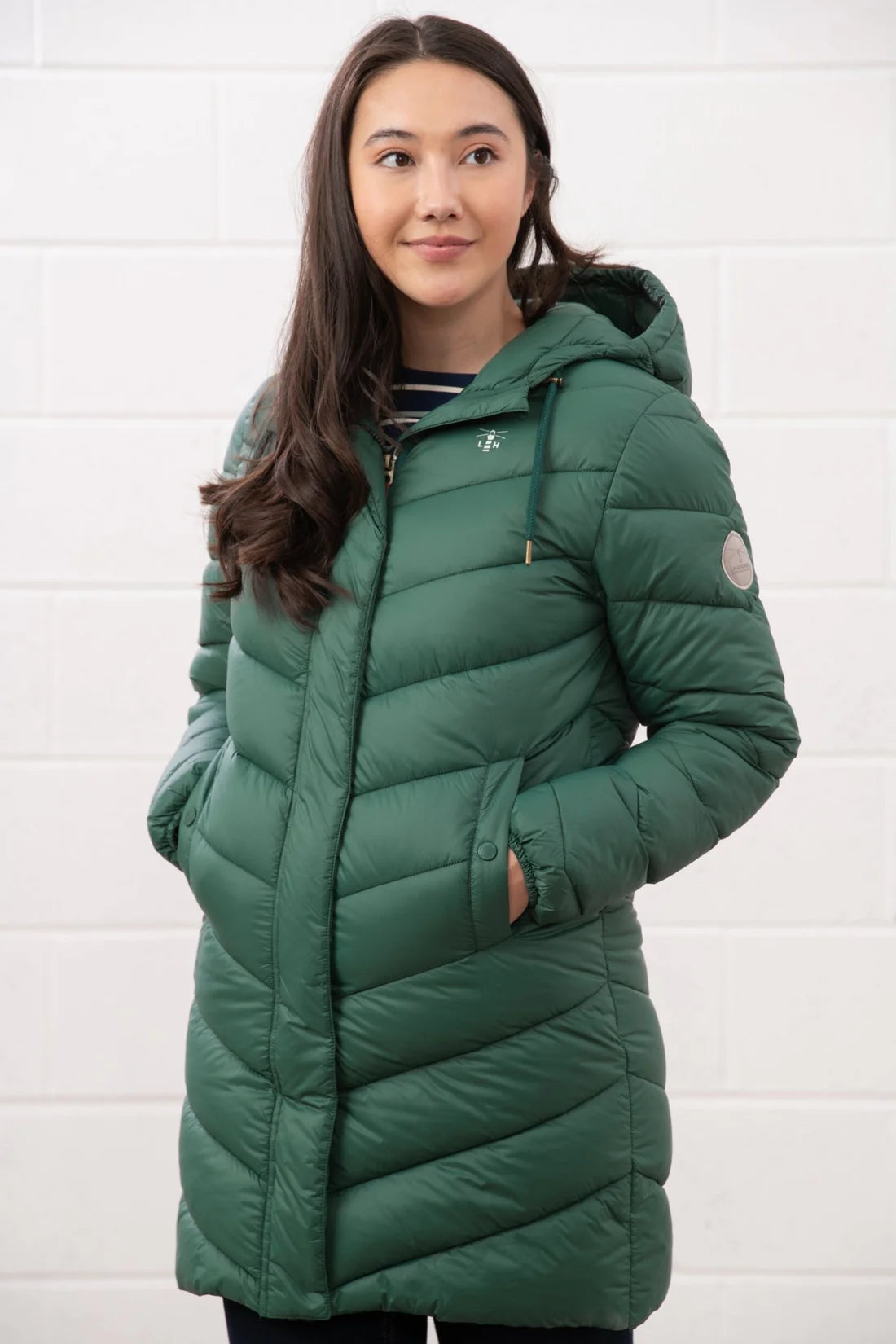 Woman wearing a green puffer jacket against a white background