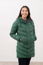 Woman wearing a green puffer coat against a white background
