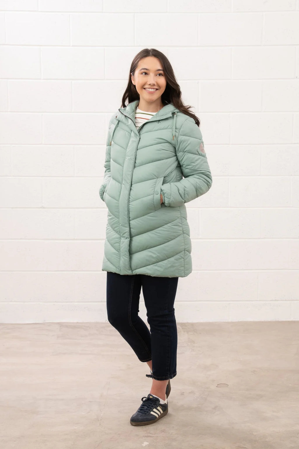 Woman wearing a light green puffer jacket against a white background