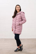 Woman wearing a pink puffer coat against a white background