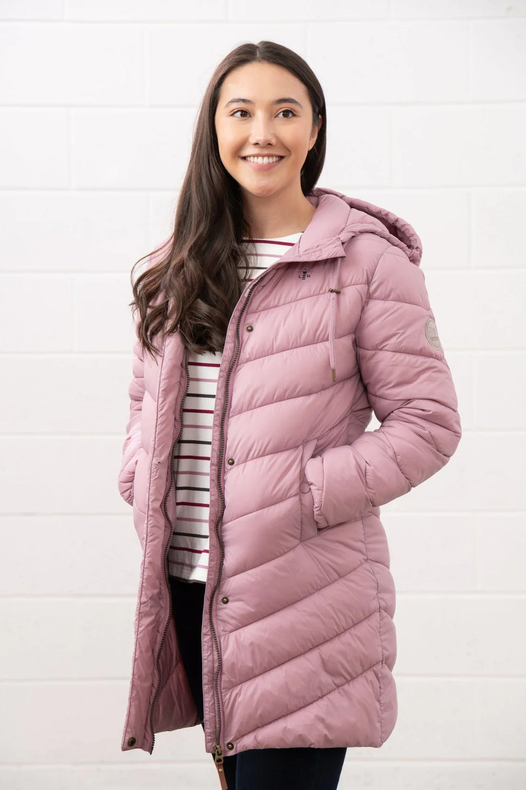 Woman wearing a pink quilted jacket against a white background