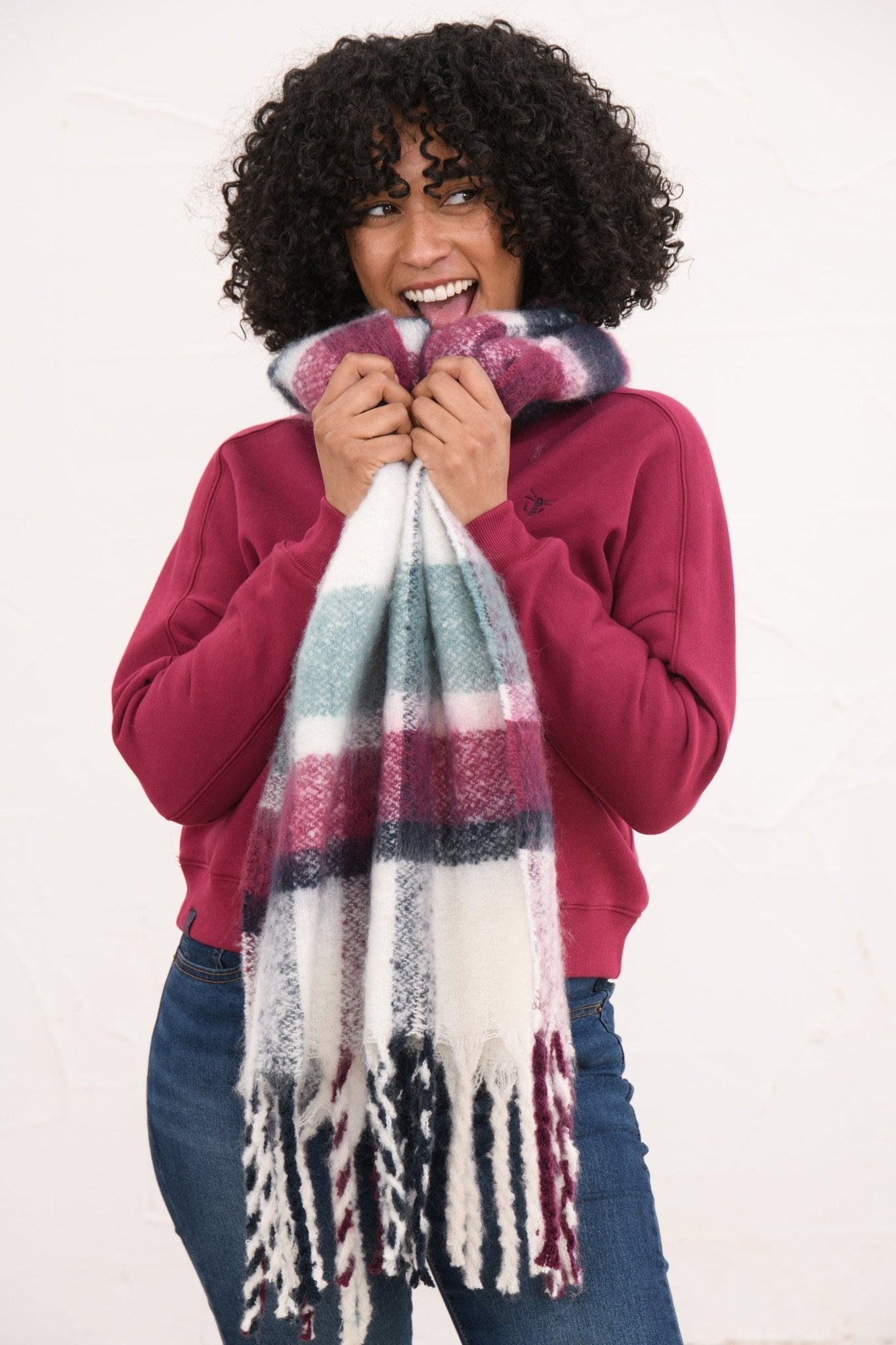 Woman wearing a colorful plaid scarf with a white background