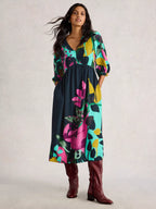 Woman wearing a colorful floral dress with brown boots on a light background