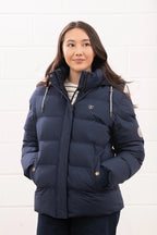 Woman wearing a navy blue puffer jacket against a white background