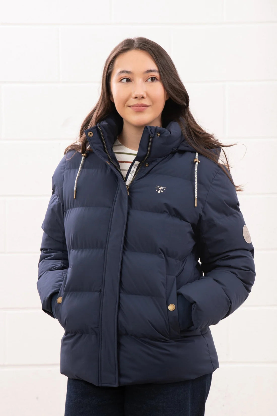 Woman wearing a navy blue puffer jacket against a white background