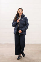 Person wearing a navy puffer jacket and pants against a white background