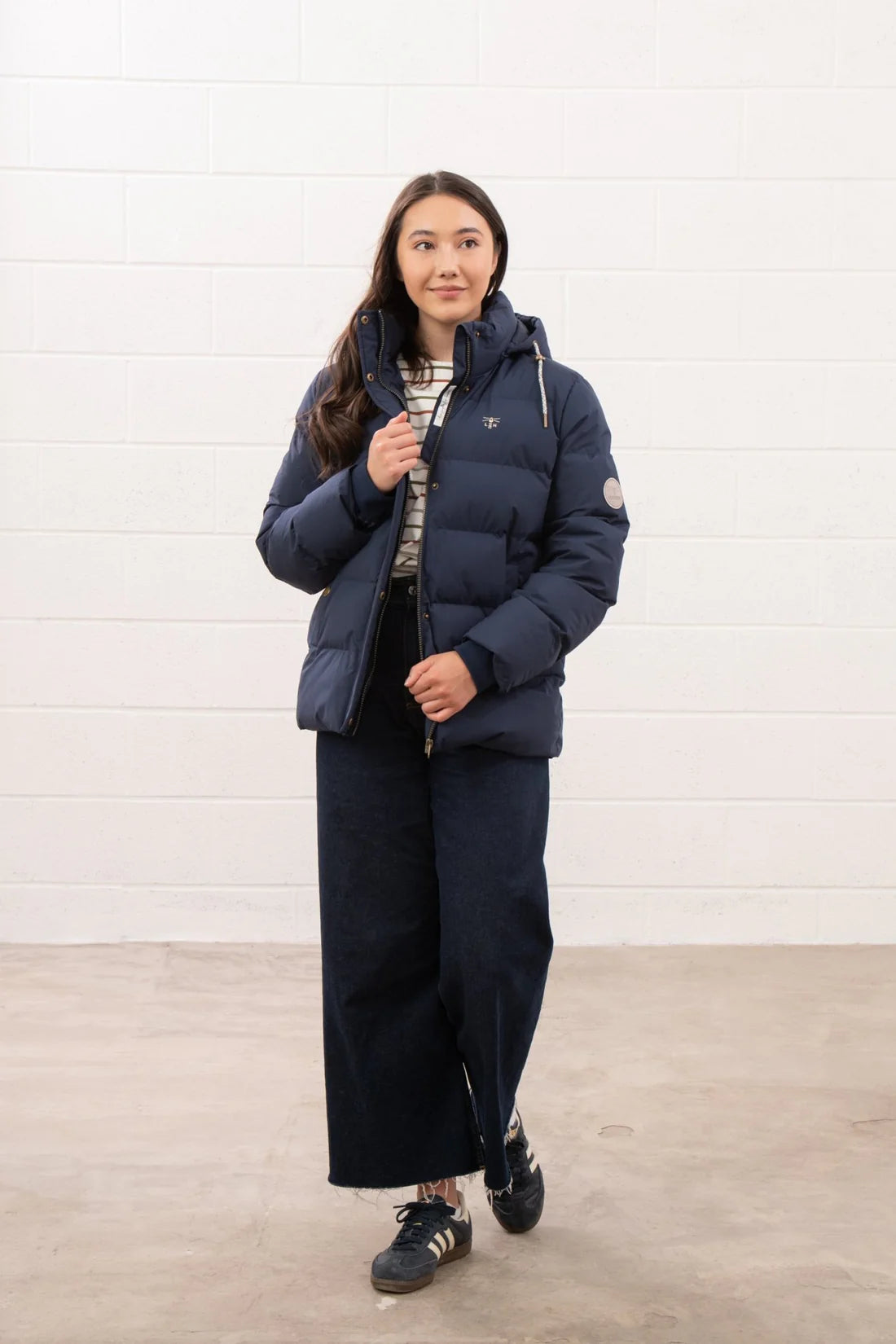 Person wearing a navy puffer jacket and pants against a white background