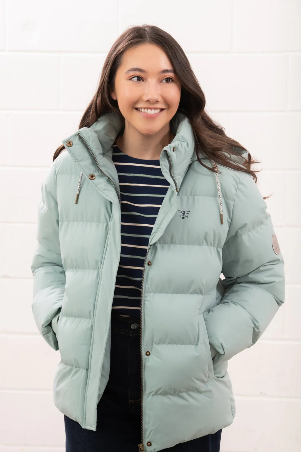 Woman wearing a light blue puffer jacket against a white background