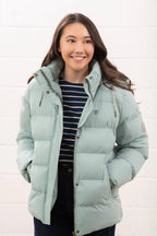 Woman wearing a light blue puffer jacket against a white background