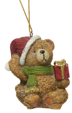 Teddy bear ornament with a red hat, green scarf, and gift box on a white background