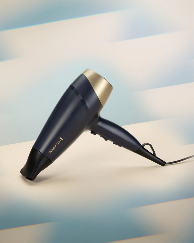 Black hair dryer with gold accents on a light surface with a blurred background