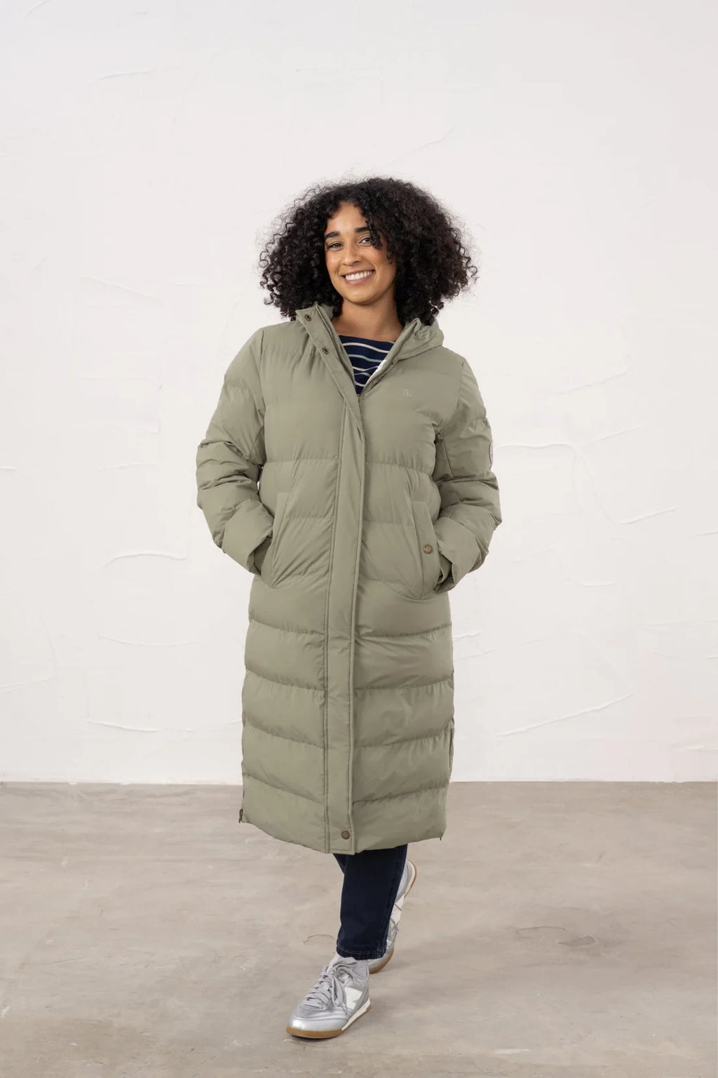 Woman wearing a long puffer coat against a white background