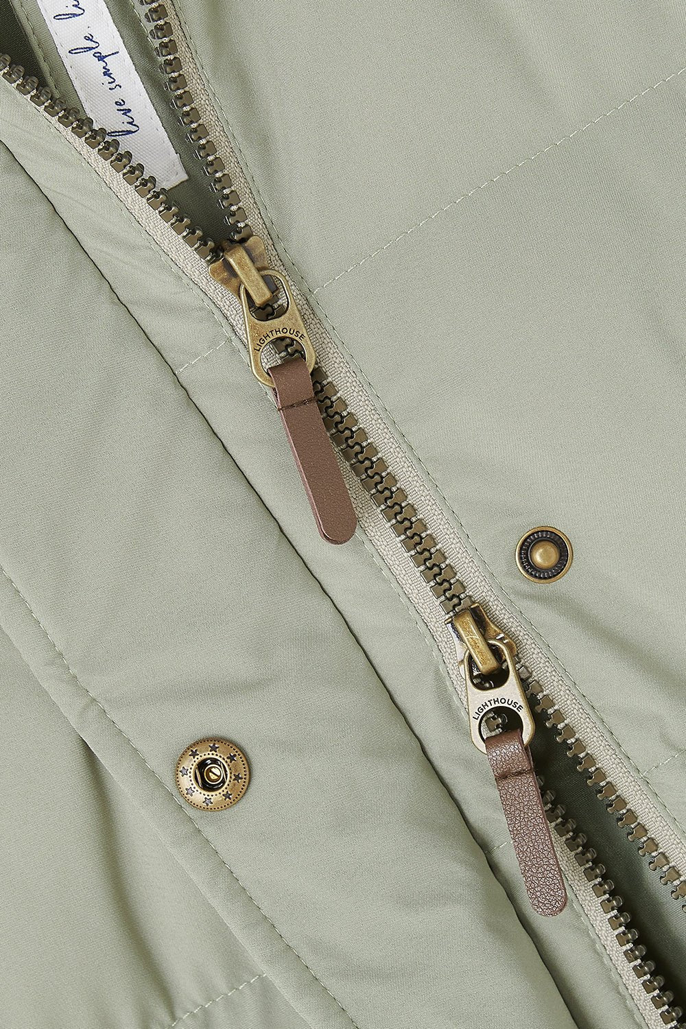 Close-up of a green jacket with a zipper and buttons on a matching background
