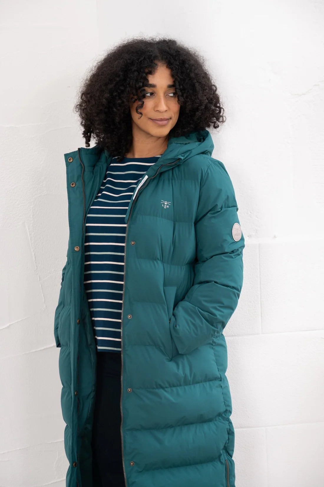 Woman wearing a teal puffer jacket against a white background