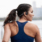 Woman wearing a blue tank top with a blurred background using the Shokz Open Move headphones